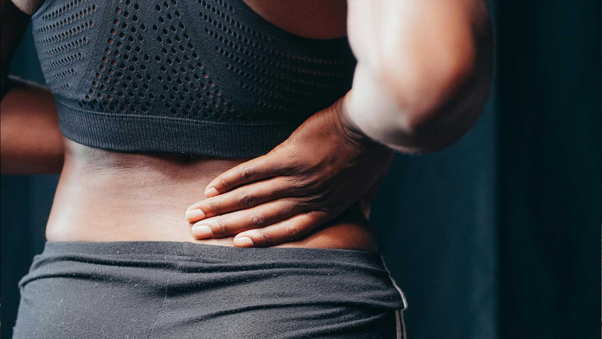 Image of a woman holding her lower back in pain