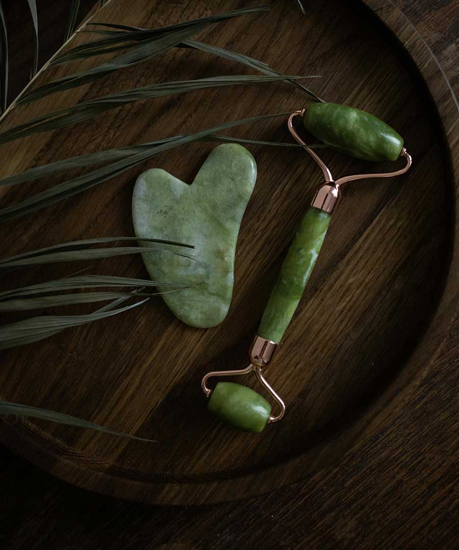Gua sha tools on a wooden table with leaves.
