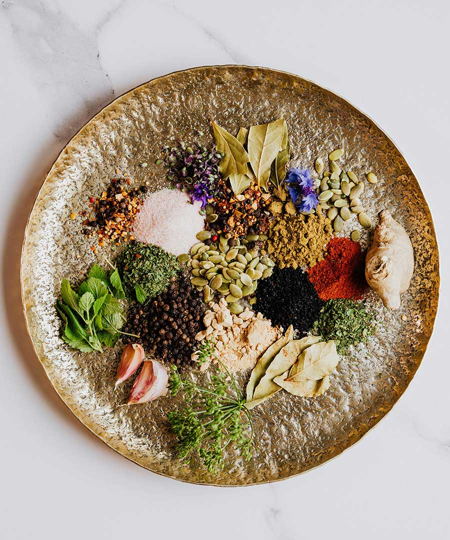 Image of colorful sides, roots, and herbs on a circular dish.